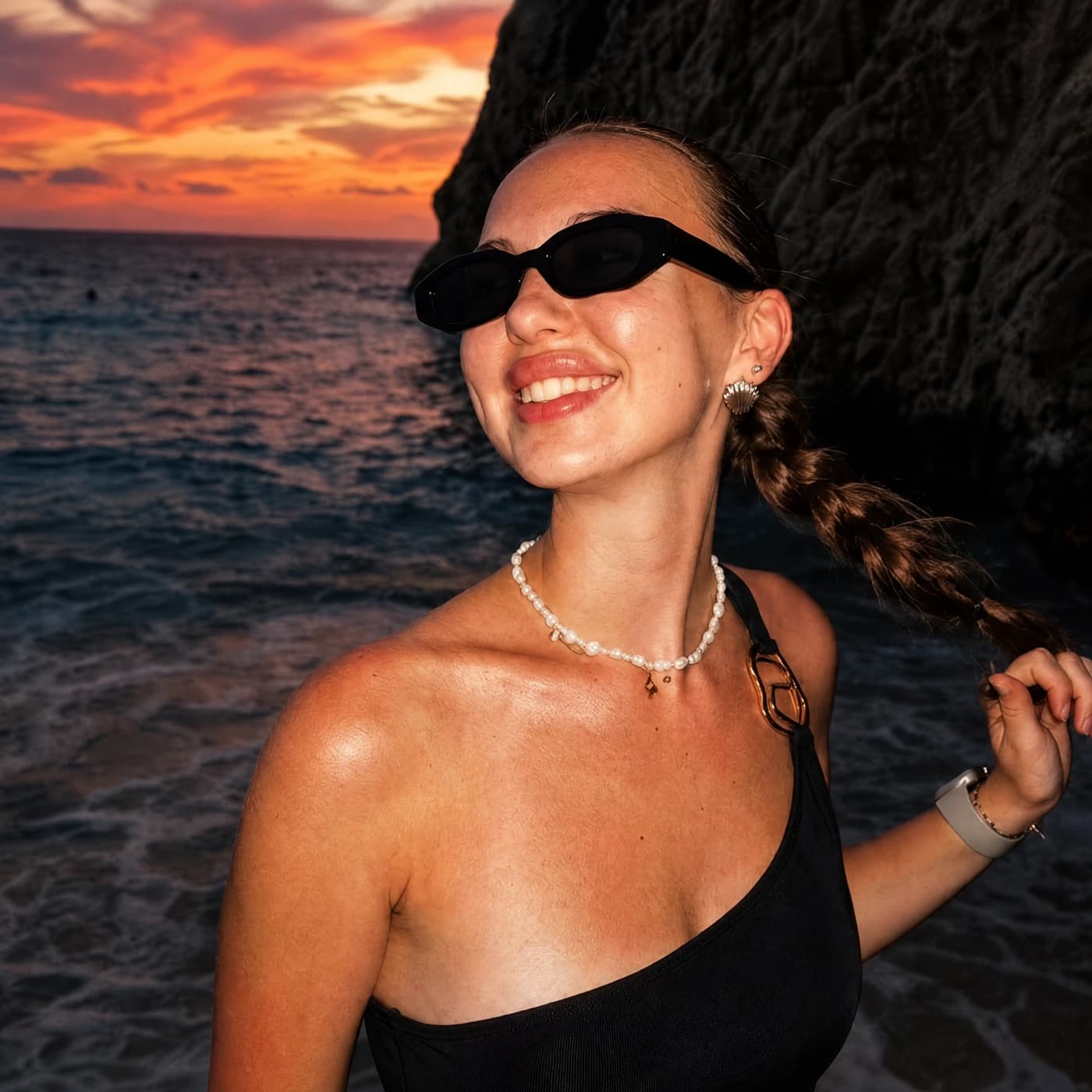 A woman in sunglasses on a beach, with the After look