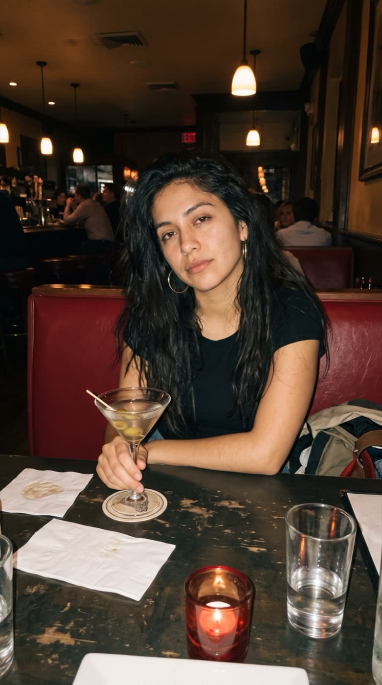 A woman at a restaurant table holding a martini, original photo